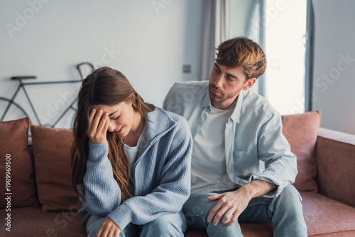 Photos Young couple on sofa after argument with man comforting upset woman in cozy livi