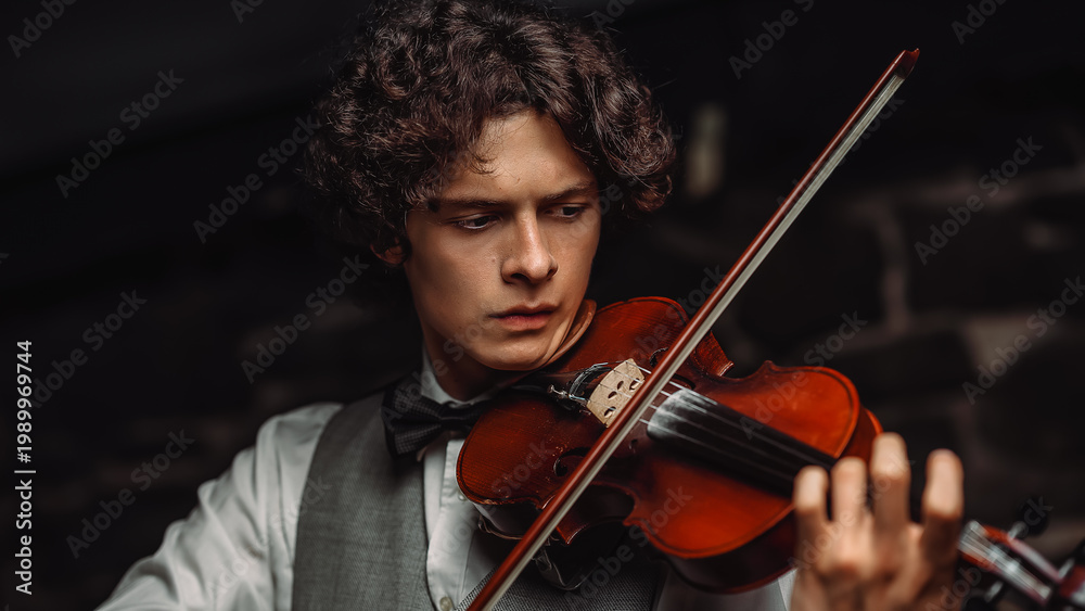 Fototapeta premium Young male violinist playing violin in elegant attire