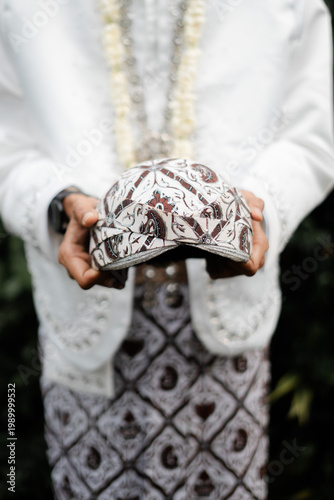 Indonesian Groom Holding a Traditional Javanese Blangkon Headpiece