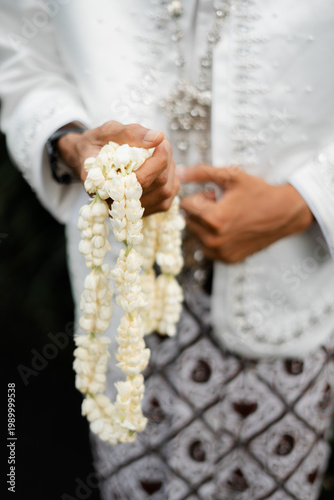 Close-up of an Indonesian Groom Holding a Traditional Jasmine Flower Garland
