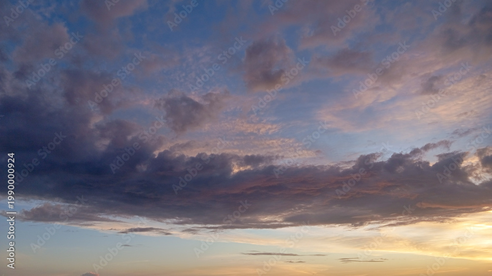 Fototapeta premium Colorful cloudscape with natural blue and golden tones during sunset, ideal for wallpaper, environmental campaigns, and inspirational imagery.
