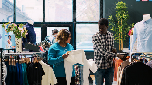 Fotografie African american couple looking at fashionable clothes, checking items material in clothing store