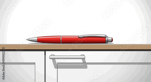 A red ballpoint pen lies on a wooden desk above white cabinets.
