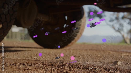 Vehicle rear wheels rolling on gravel, kicking dust and displaying magenta particles as tech data