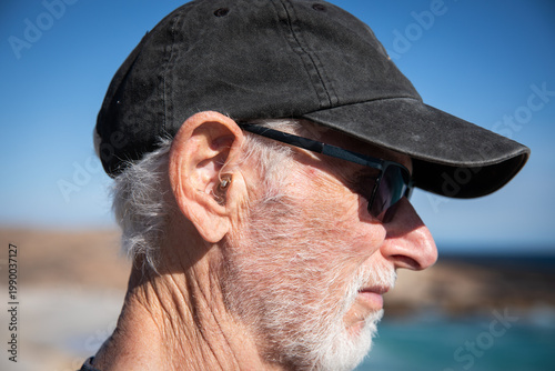 Elderly man wearing sunglasses and baseball cap