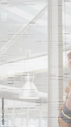 Vertical video: Woman receiving business call while standing by glass wall, atrium beams