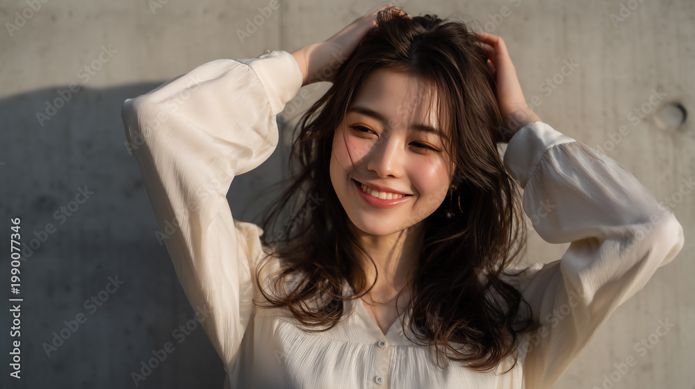 Naklejka premium Cheerful Japanese woman touching her hair with a bright smile in natural light