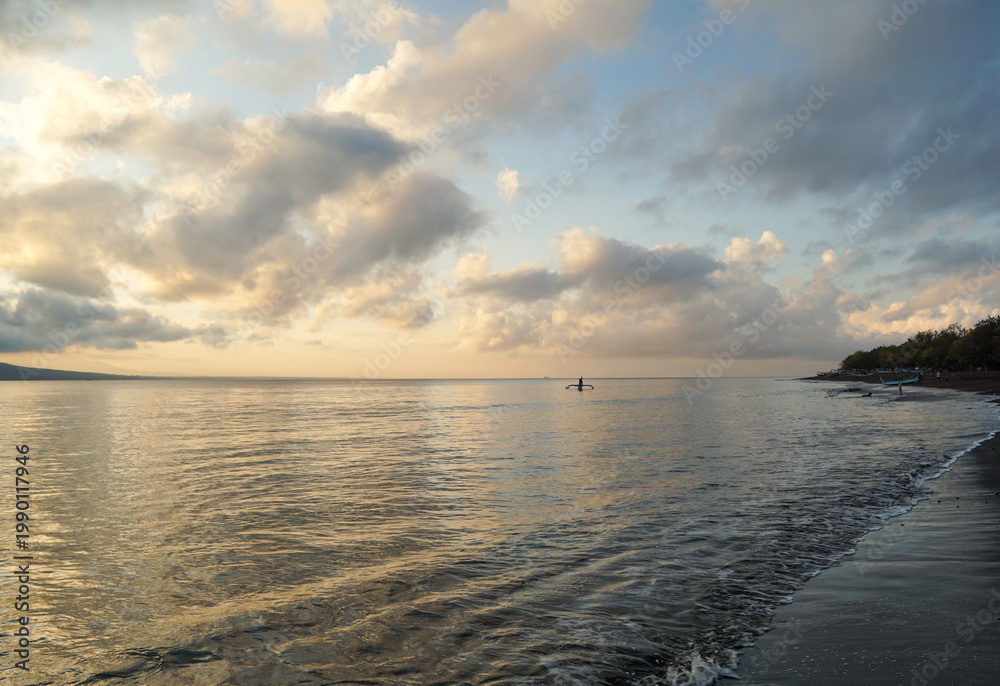 Fototapeta premium Small fishing boat sailing on the calm Bali Strait during golden sunrise, Banyuwangi. 