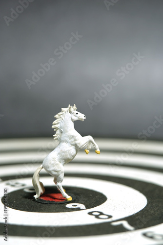 Miniature of white prancing horse standing in the center of dartboard