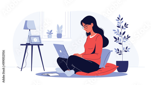 Young woman sits comfortably on a floor cushion while working on her laptop in a cozy room with plants and a lamp.