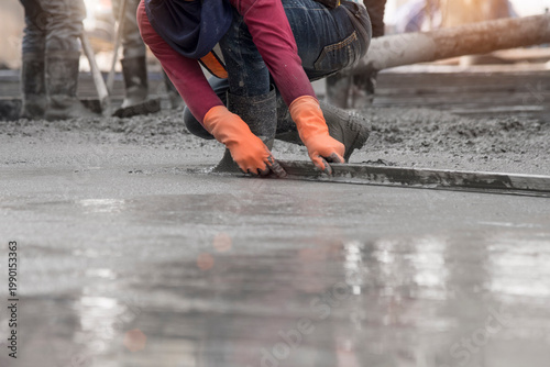 Photos Construction worker troweling wet concrete on a top of concrete floor slab new c