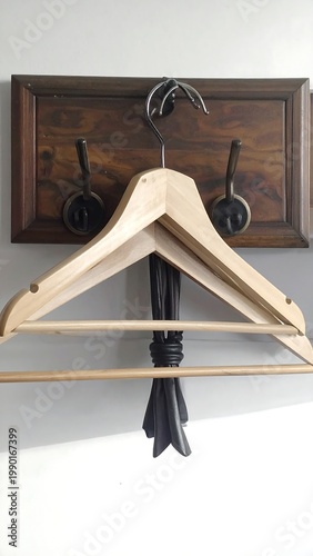 A wooden hanger hangs from a hook on a wooden board
