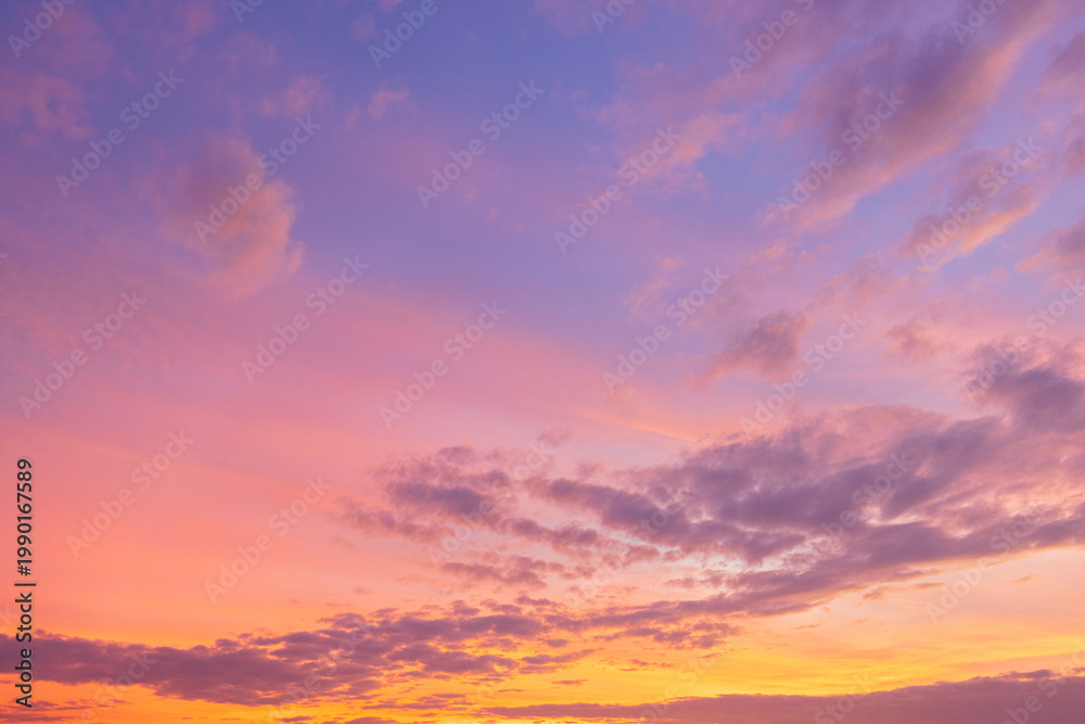 Naklejka premium Beautiful sunset sky with golden light and purple clouds over the horizon,Dramatic sunset sky background with soft orange sunlight and scattered dark clouds during twilight. The evening atmosphere.