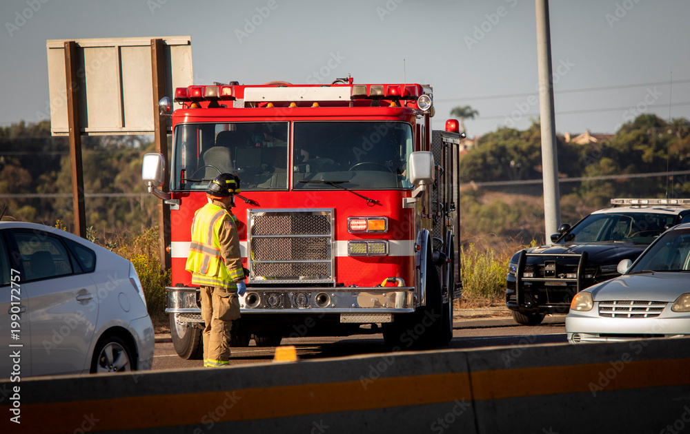 Fototapeta premium Firefighters and a fire truck at an accident scene on a freeway