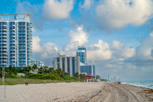 Miami South Beach coastline with lifeguard tower and skyline. Sandy beach with purple lifeguard stand and luxury high-rise buildings along the Atlantic coast.