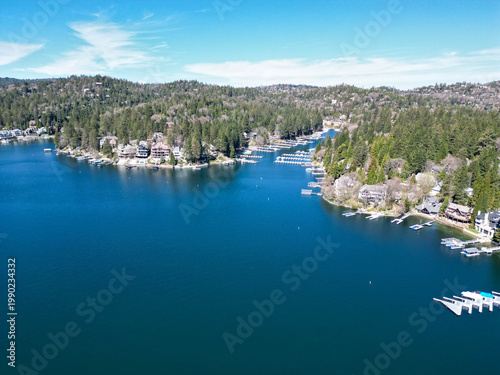 Foto Drone view of a mountain lake surrounded by pine forest and waterfront houses with docks and marina