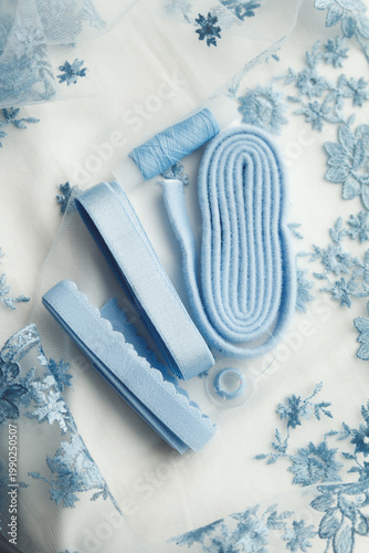 A close-up photo of tailor's tools: blue lace, elastic, spool. Photo grain added.