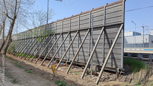 urban noise barrier wall with metal supports along roadside infrastructure