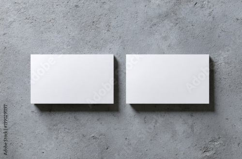 Two blank white horizontal cards on a rough gray concrete surface, top-down view