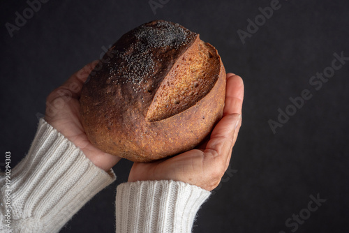 Hands holding freshly baked rustic bread loaf, homemade bakery concept