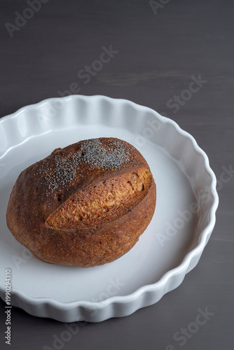 Minimalist composition of artisan bread loaf on white plate