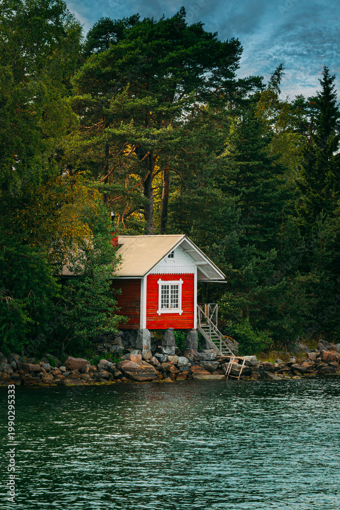 Fototapeta premium Traditional Red Cabin on a Rocky Shoreline