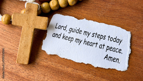Prayer for guidance to the Lord text on white prayer note beside wooden cross.