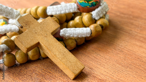 Holy Rosary placed over rosary beads on a warm wooden background representing faith and devotion.