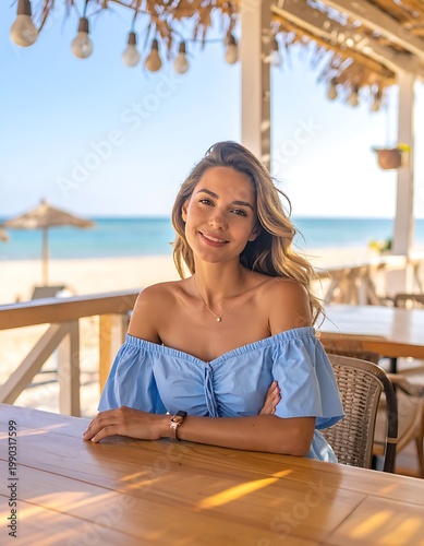 A woman sits at a wooden table on a sunny beachside patio