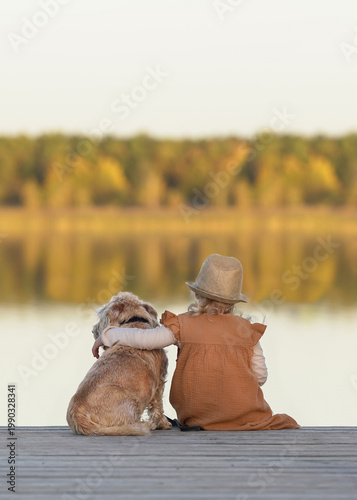 Little Girl Hugging Her Dog on a Sunny Spring Beach Pier