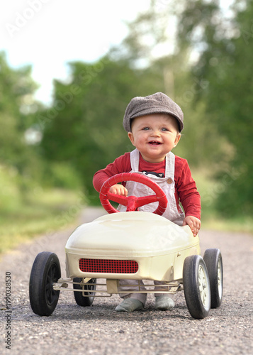 Joyful Little Boy Riding a Pedal Car in Spring Sunshine