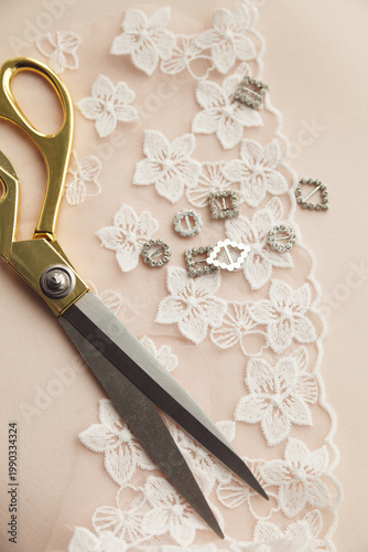  A close-up photo of tailor's tools: white flower lace, decorations, scissors. Photo grain added.