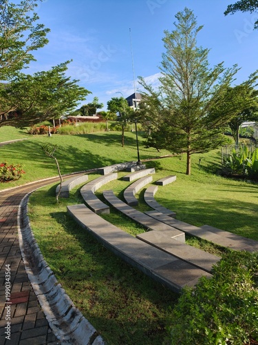 Bild auf Leinwand Modern stone amphitheater seating in a green public park under a blue sky