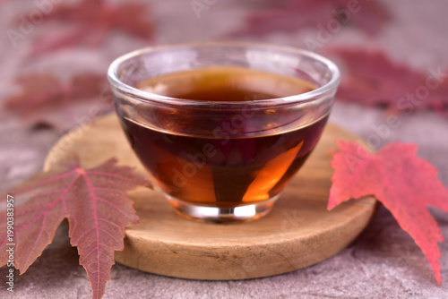 Maple syrup in a small glass bowl on a wooden tray. Close-up.