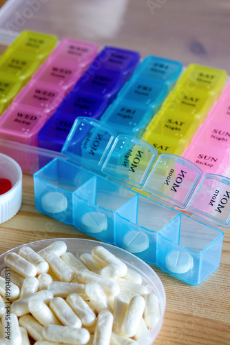 colorful weekly pill organizer with labeled days and capsules on table