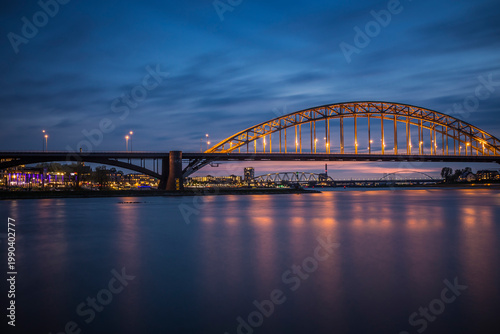 Obraz na plátně Nijmegen, a town in the Netherlands situated on a river in the evening at the blue hour, with the all the lights on