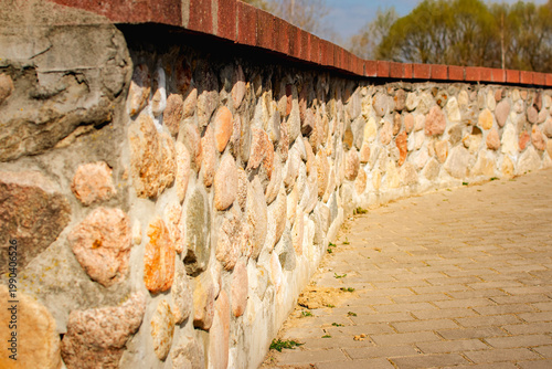 Photography decorative natural stone retaining wall with brick top edge and paved walkway in