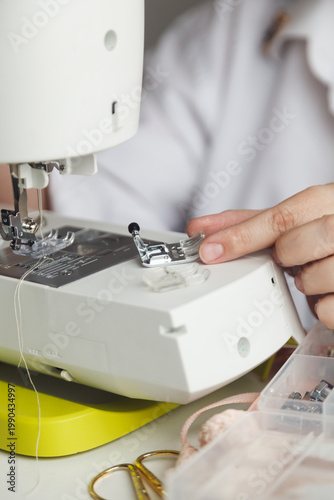 Sewing machine close-up with hand adjusting presser foot for textile work