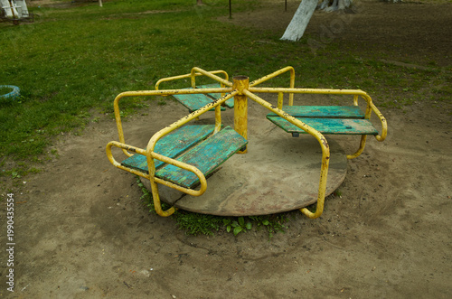 Old yellow merry-go-round sits in an empty playground during a cloudy day in a quiet park