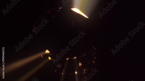 Abstract dark crystal sphere rotating with golden light rays and glowing bokeh flares seamless loop