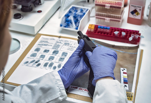 A forensic police officer examines a firearm as evidence in a homicide case at a forensic laboratory