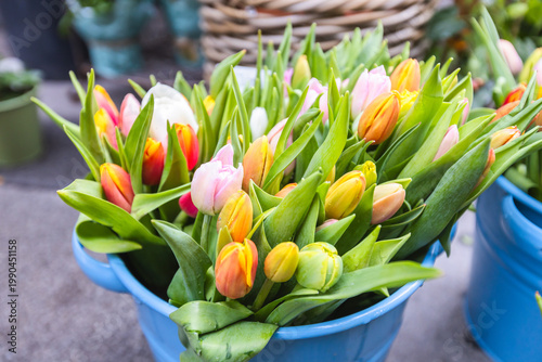 Foto Vibrant spring tulip bouquets in a bucket at an outdoor market.
