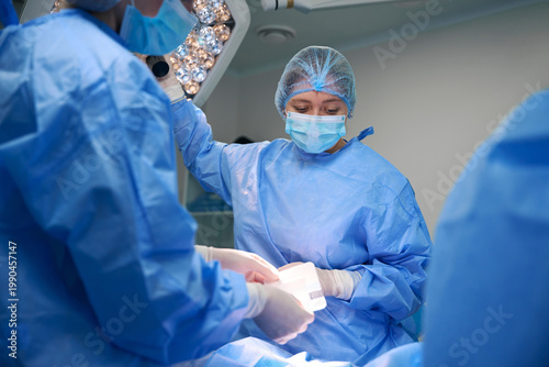 Three women performing surgery in a sterile operating room