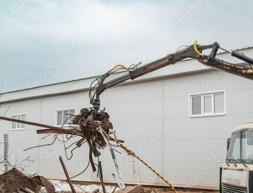 Photos A hydraulic grab transfers scrap metal into a container at the industrial site