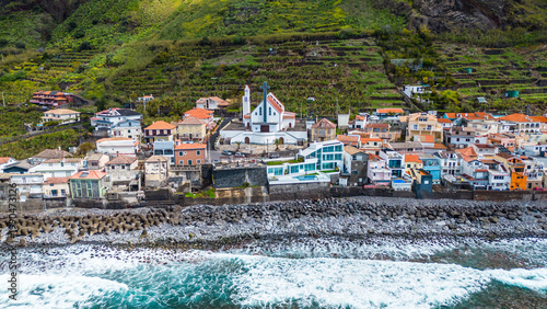 Paul do Mar, Madeira: A vibrant coastal village nestled against lush green terraces, with crashing Atlantic waves and a prominent church.