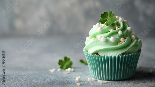 Green cupcake with whipped cream and clover decoration sits on a gray surface. It's a festive treat for a card.