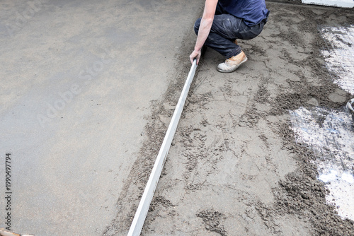 Photography Worker leveling concrete with screed for slab foundation