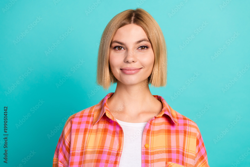 Fototapeta premium Smiling young woman portrait in casual plaid shirt with blonde bob haircut against turquoise studio background