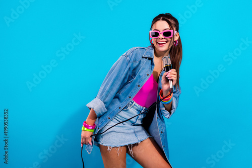 Vászonkép Young pop singer performing with microphone in vibrant retro pink and denim outf