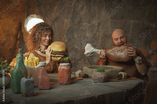 Primitive stone age couple having a delicious lunch in their cave